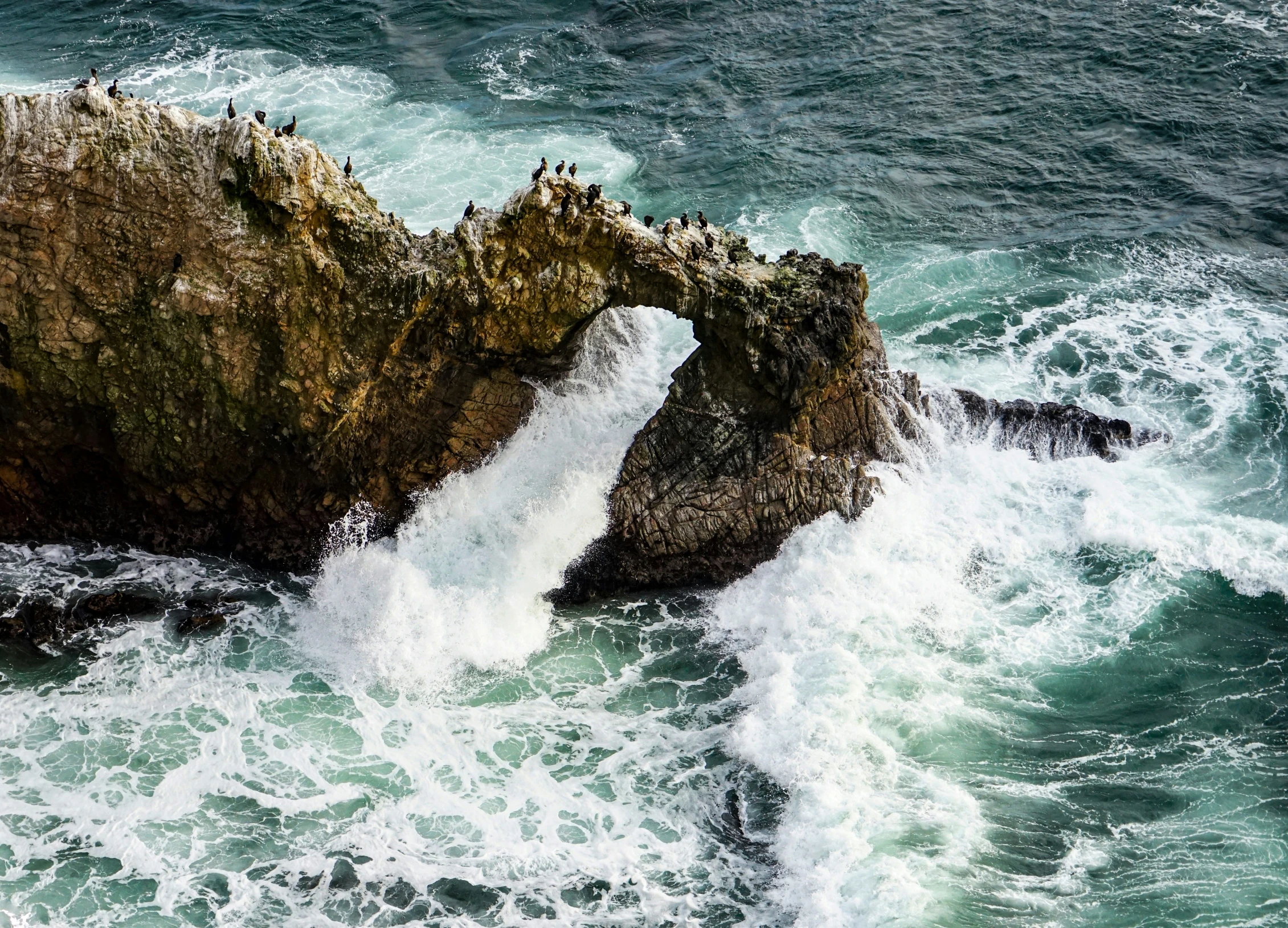 an aerial view of a waterfall near a large rock