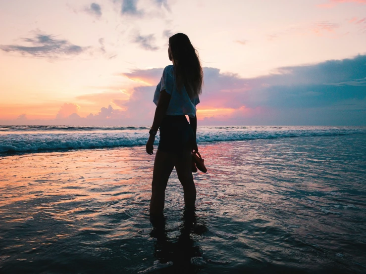 a woman standing on the shore of a beach