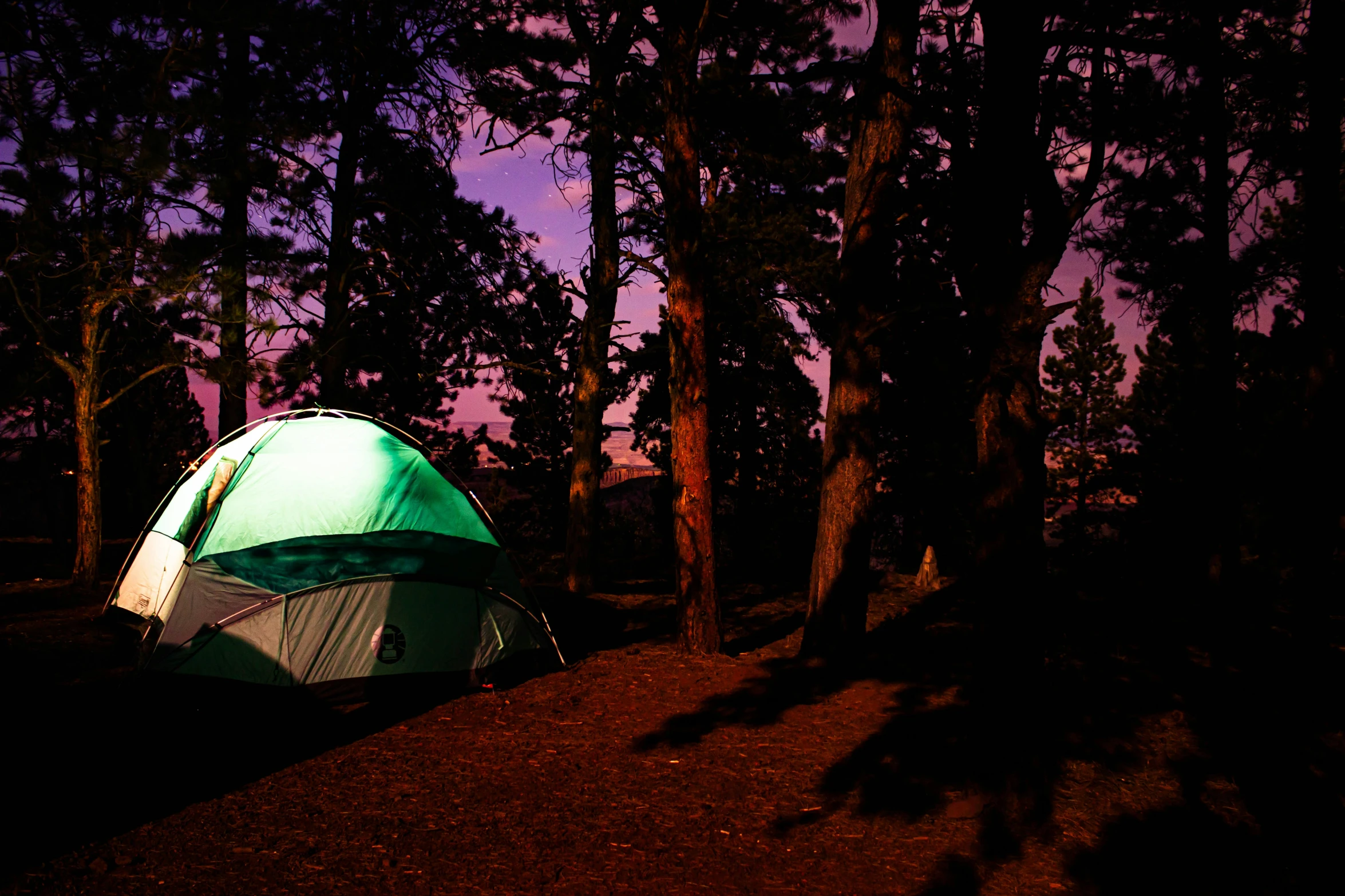 a lit up tent in the dark next to some trees