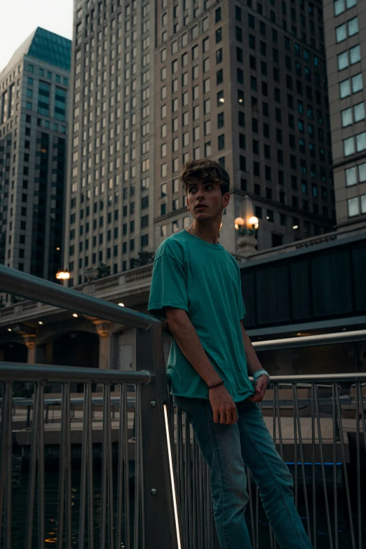 the man is standing on a bridge in front of tall buildings