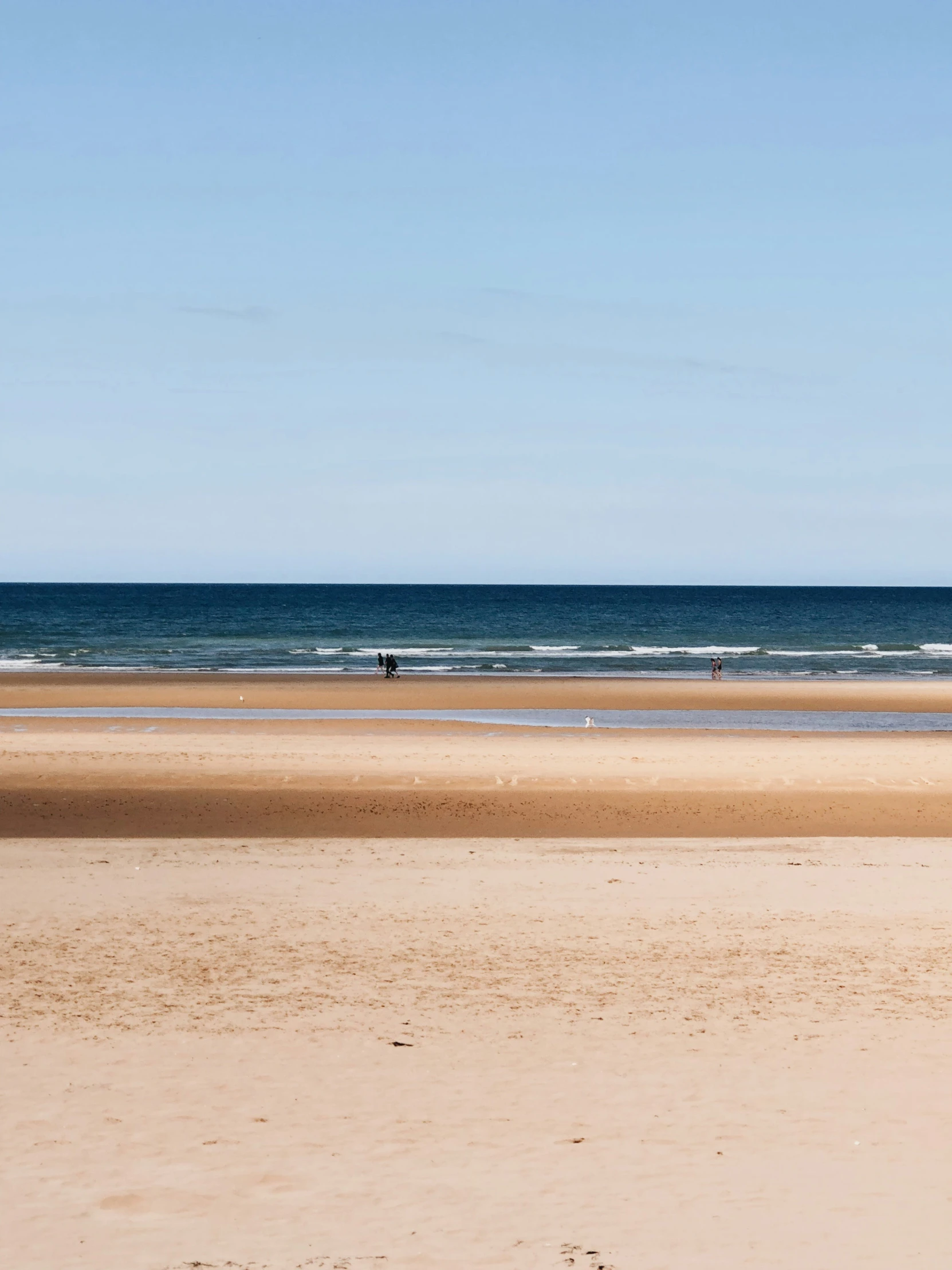 surfers are walking on the beach toward the ocean