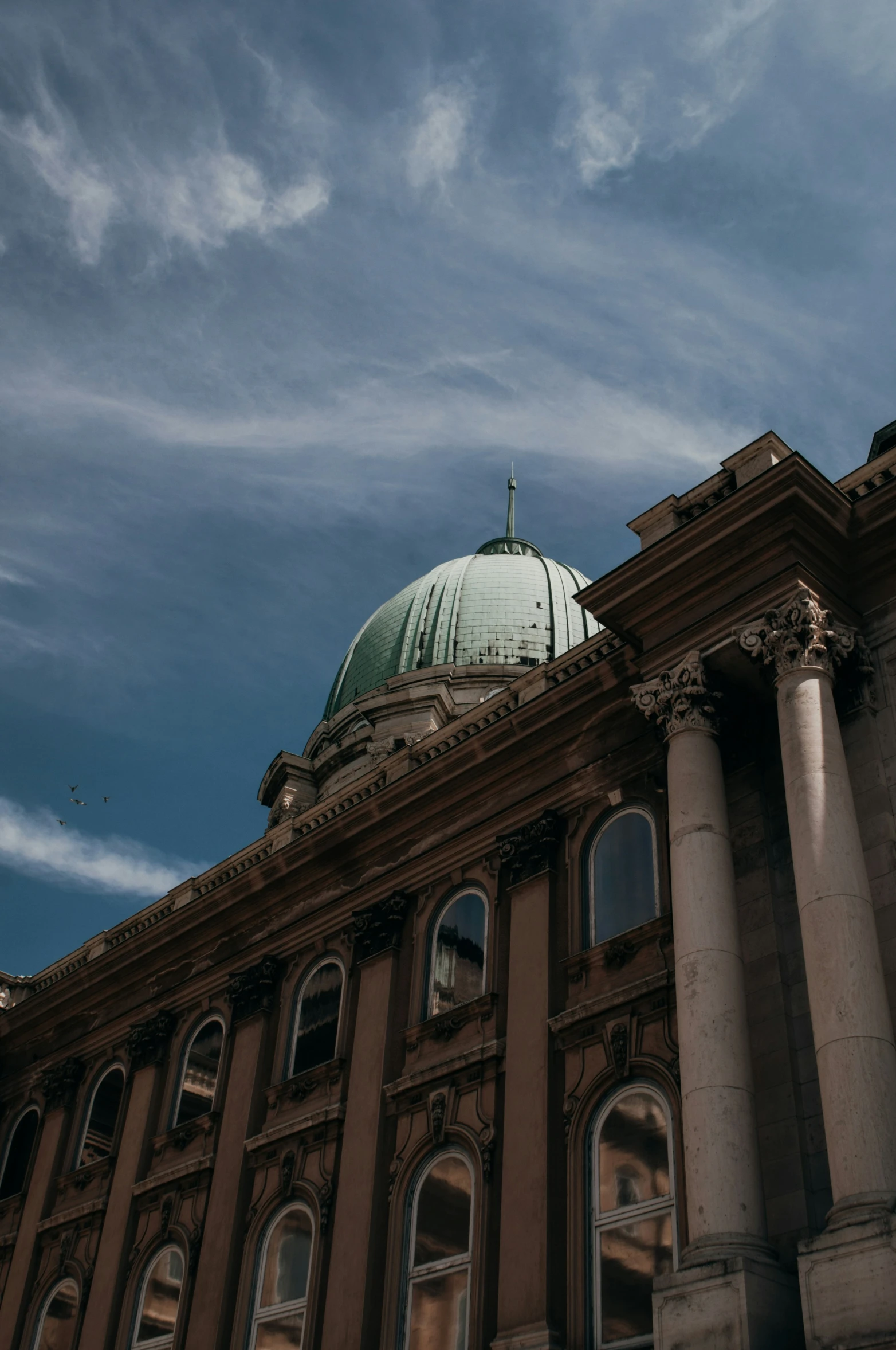 the top of an old building that looks like it has a green dome on top