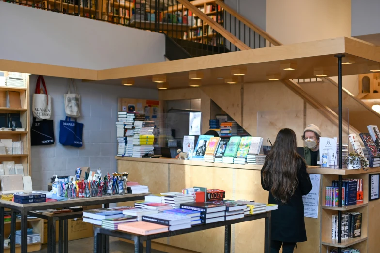 a girl stands at the counter of an open book store