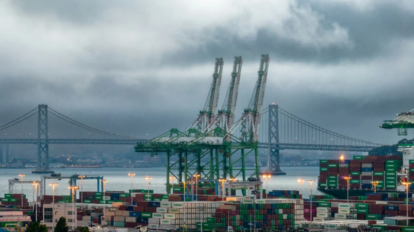 the containers are stacked up in a port near a bridge