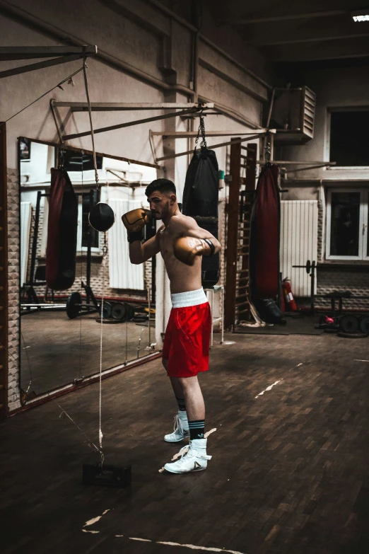 a man is standing in a gym holding boxing gloves