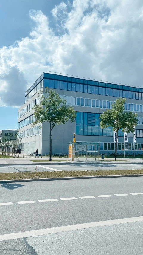 an empty street with trees on both sides of the street and large building with three floors