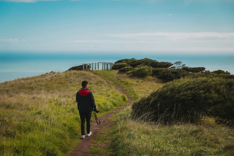 man walking on trail next to open water