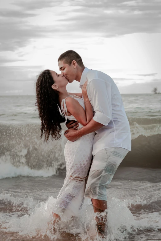 an engaged couple are kissing while in the ocean