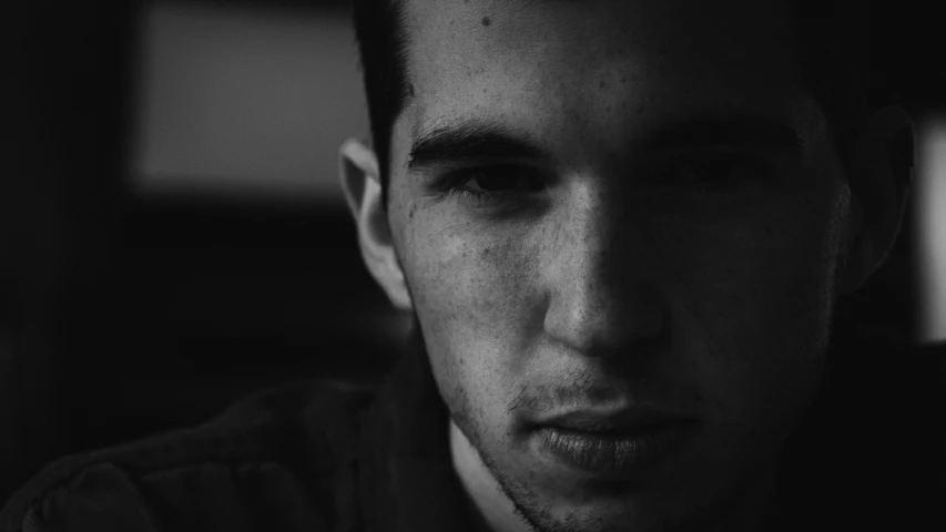 a man staring at the camera in a dark room