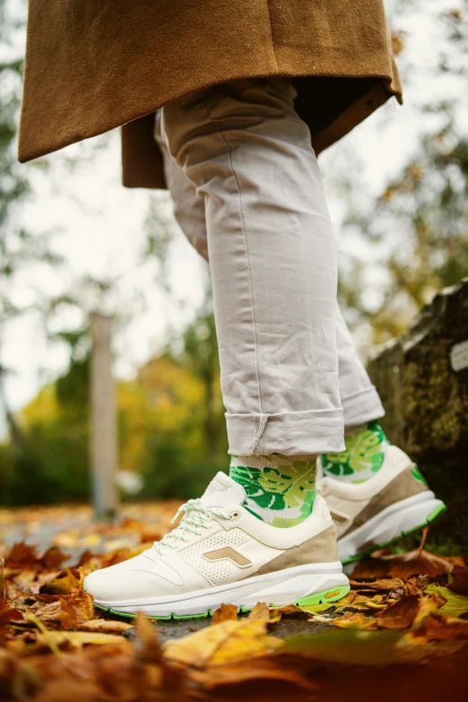 a person with green and white sneakers on leaves