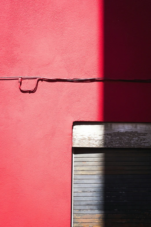 a red wall with a small rectangular object at the corner