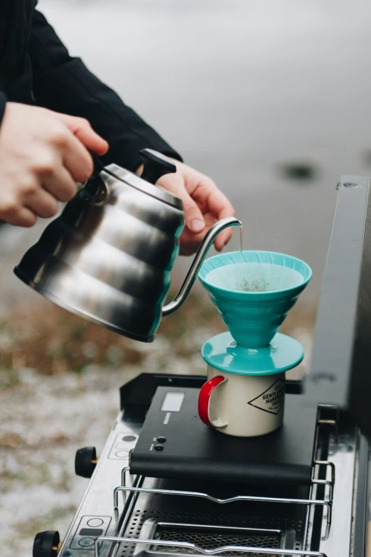 a person pouring coffee from a pot into a mug