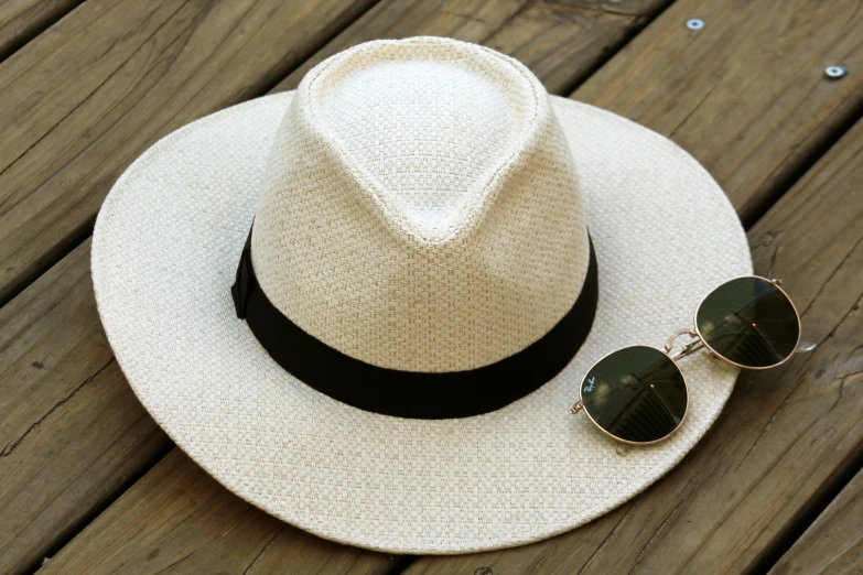 a hat and sunglasses sitting on a wooden surface