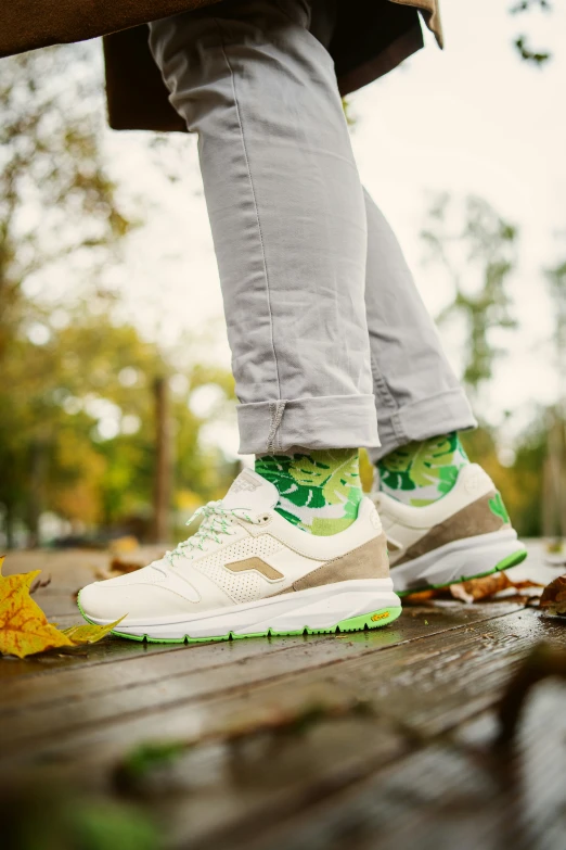 the legs of someone with green and white sneakers