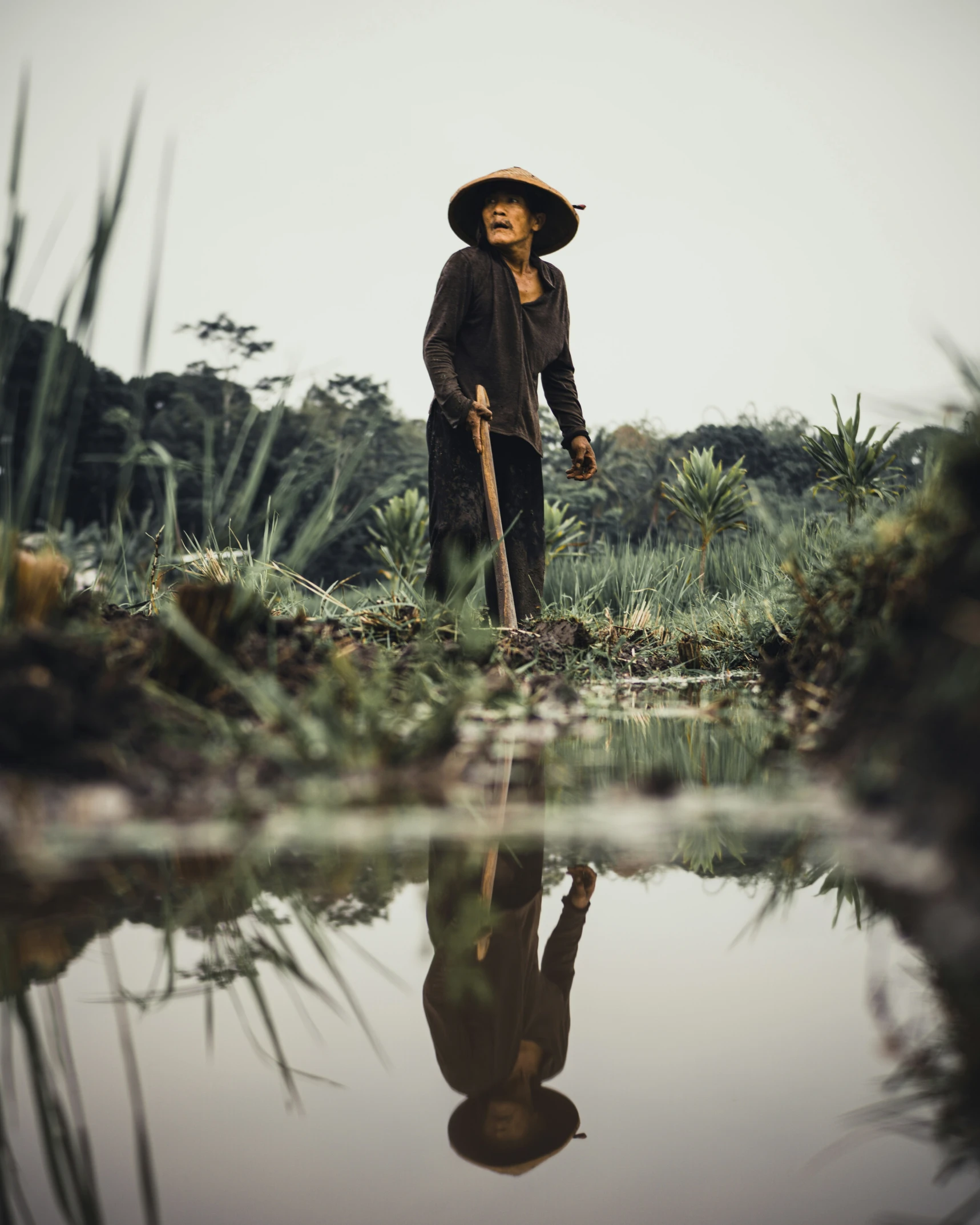 the old man is standing in the water, holding a stick