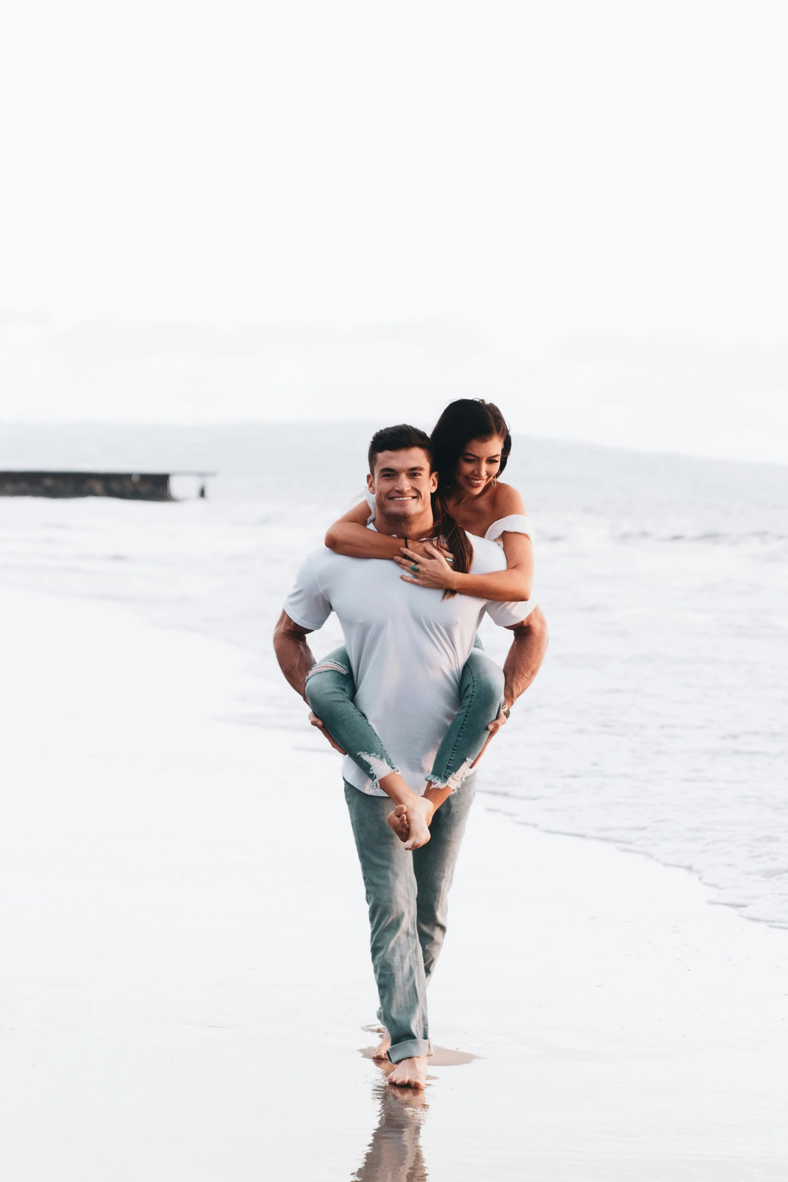 a young man and woman walking on the beach together