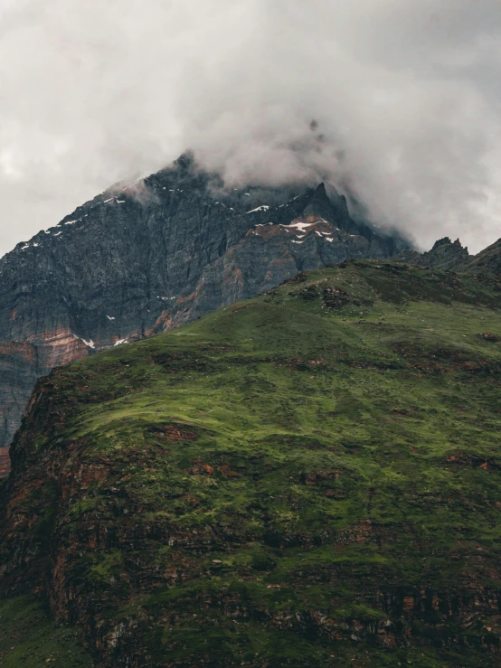 a mountain covered in grass with a cloudy sky