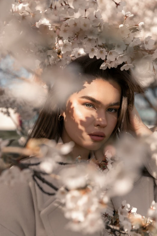 a woman is shown posing behind a tree full of flowers