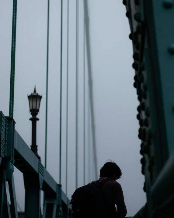 a person sitting on the ground looking at the bridge