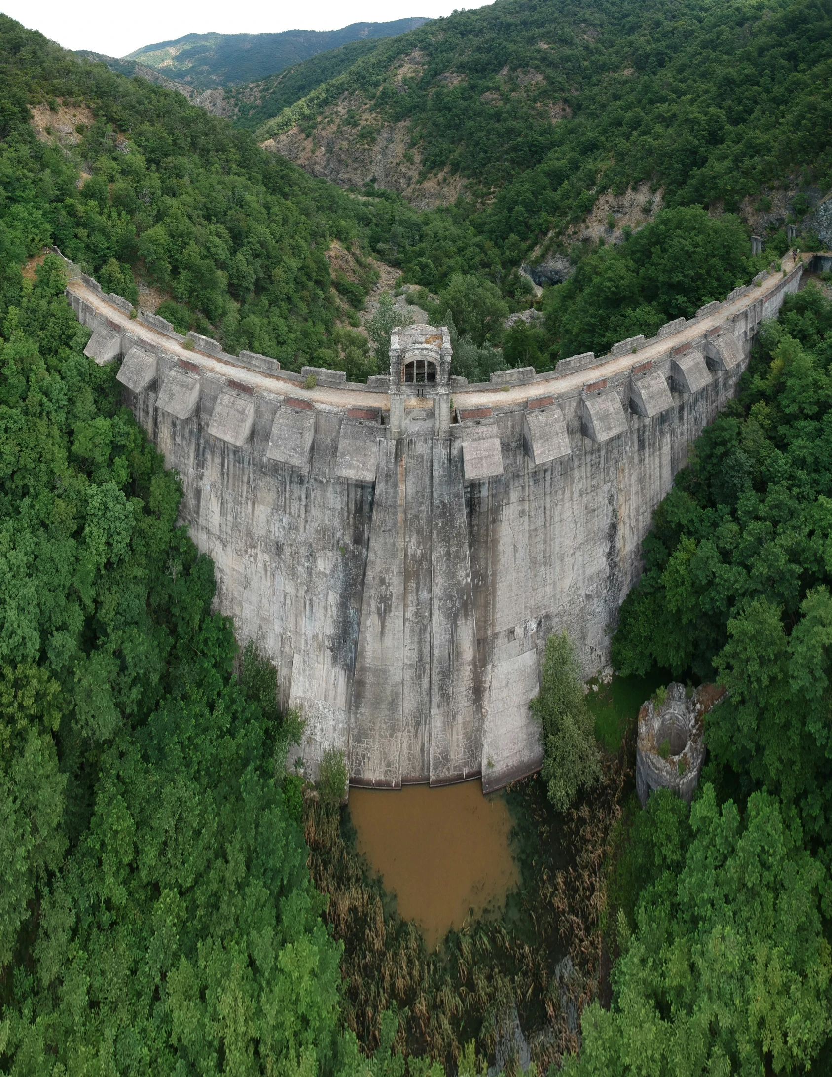 a large stone wall over a forest and a river