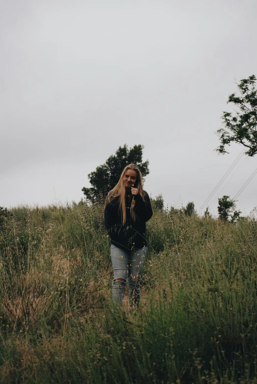 a woman standing in a field with trees and grass