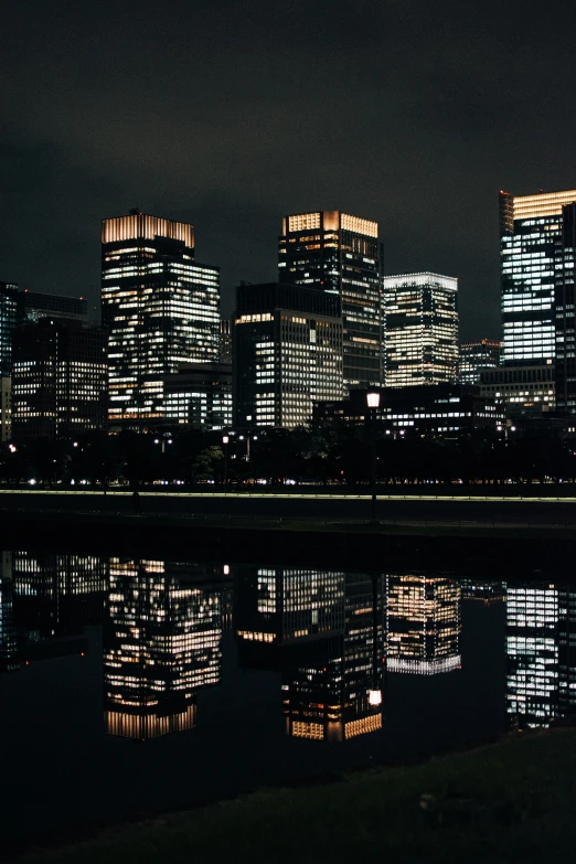 several tall buildings lit up at night over water