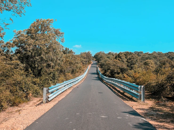 an empty road is on the side of a hill