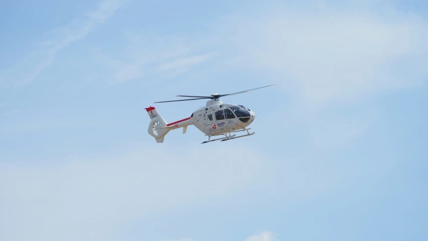 the helicopter flies in the blue sky in the daytime