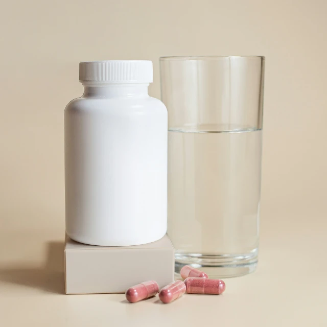 white square block next to water glass and pill bottles