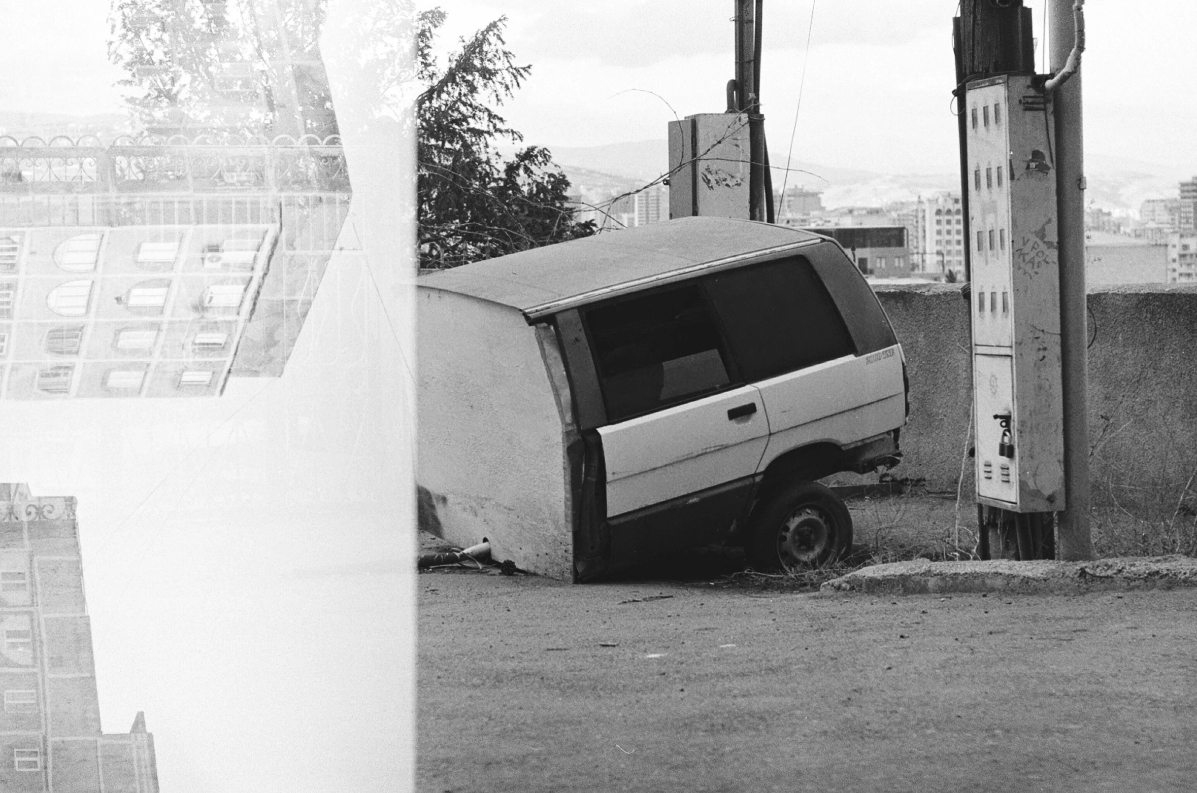 an abandoned van sits next to a building with a broken door