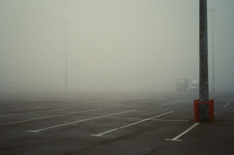 a parking lot filled with cars covered in heavy fog