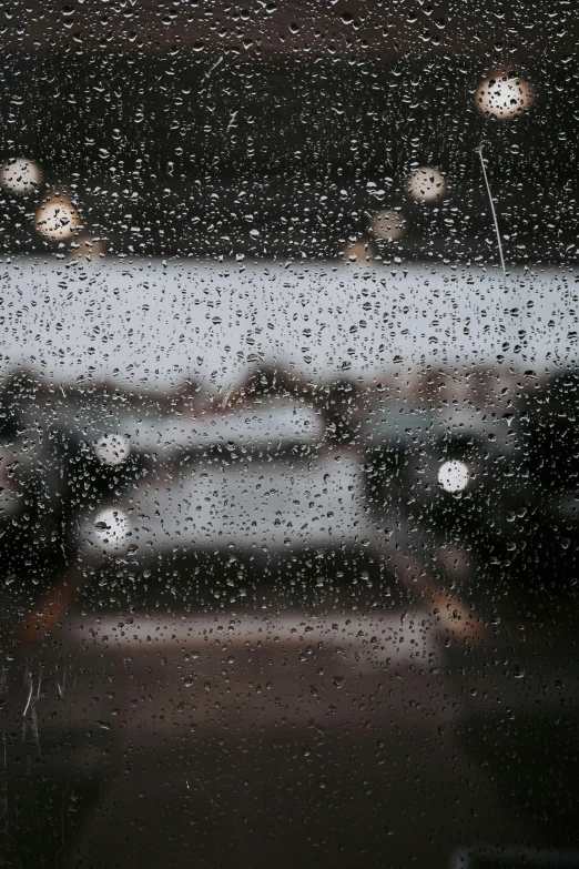 rain is seen in the glass of a car and some lights