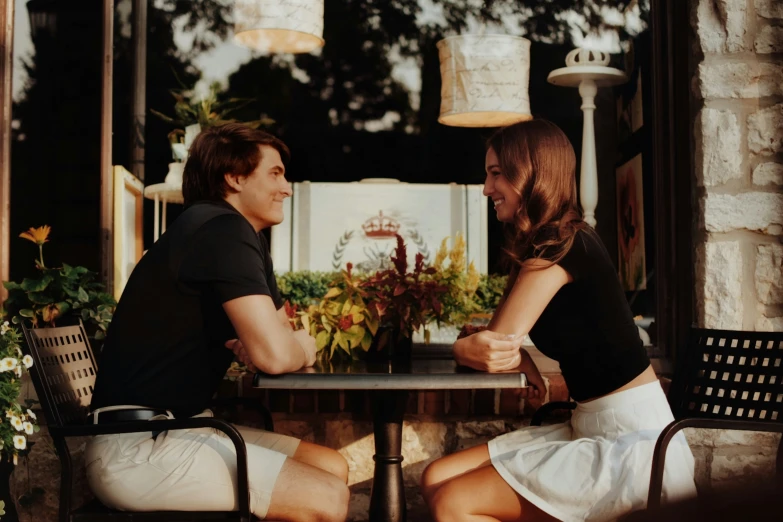 two people sitting at a table with one woman talking