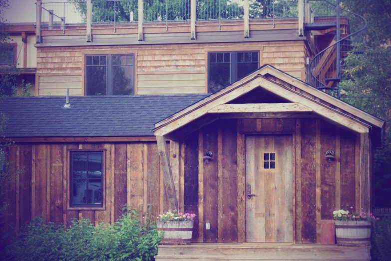 wooden cottage next to a green hillside and trees