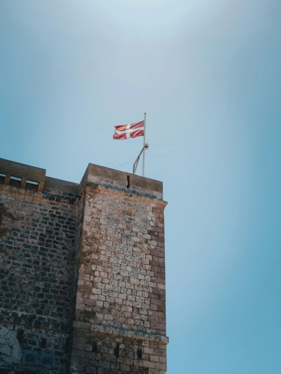 the view from below is looking up at a red flag on the top of a building