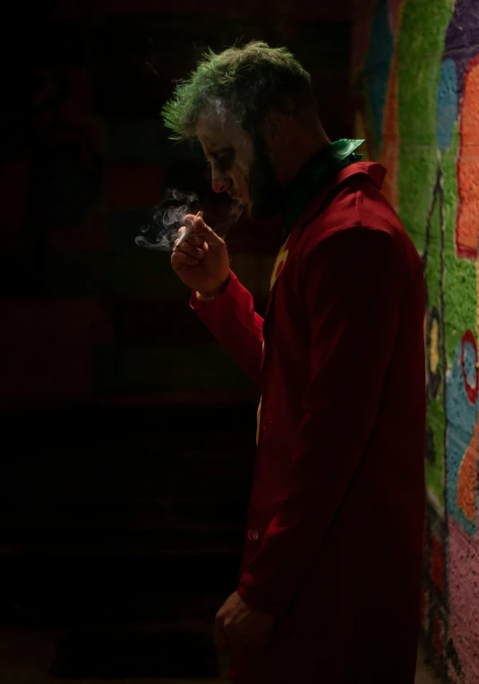 a man in a red hoodie is smoking and standing