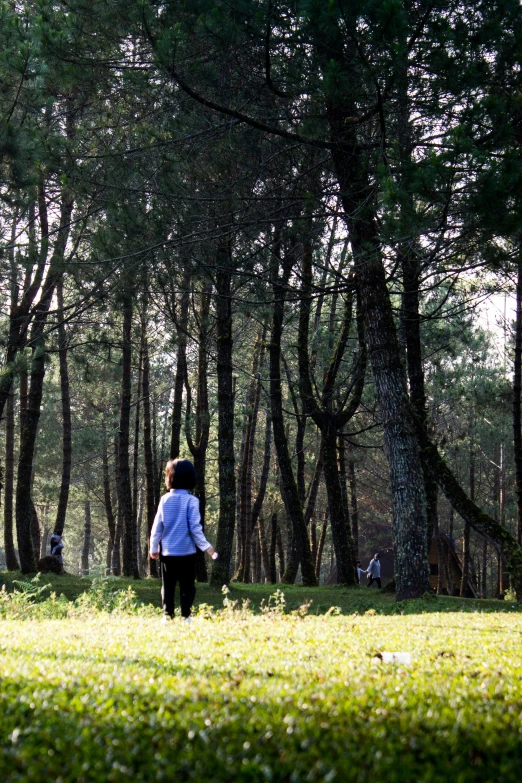 the young woman in the white shirt is walking through the park