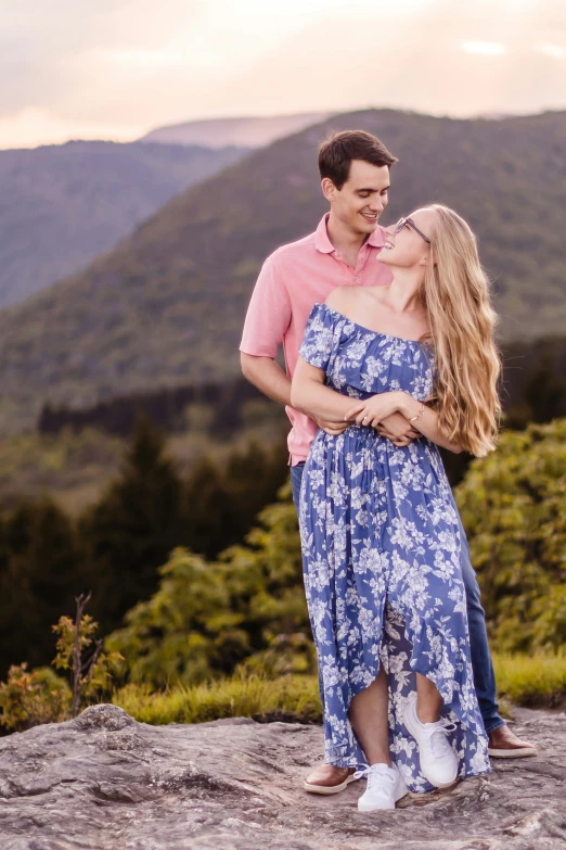 a man is hugging a woman while she stands on a mountain top