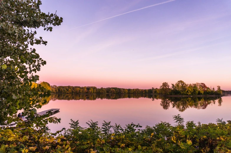 the beautiful pink sunset over a lake and tree line