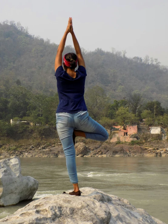 a woman standing on a rock and doing yoga