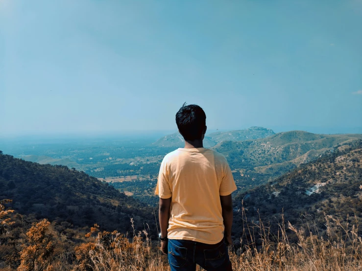 man looking out over the valley from atop a mountain