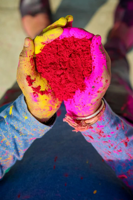 the hand holds a mound of colored powder