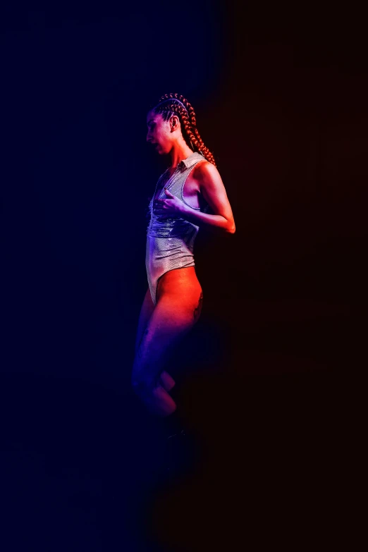 a woman standing in the dark wearing a white and blue top