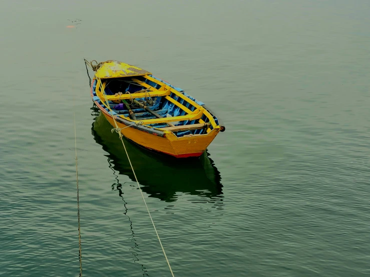 a boat with yellow hull tied up to a wire