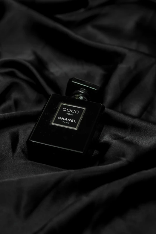 closeup s of black perfume bottle on a black silk texture