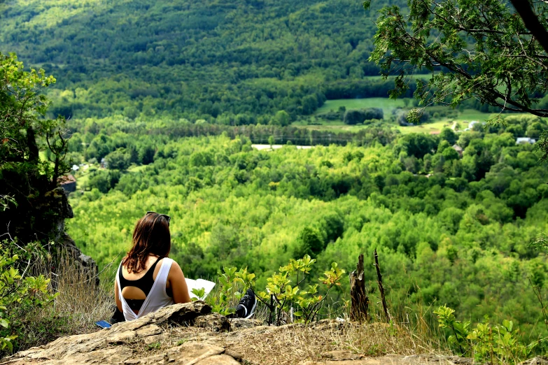 a woman is sitting on a hill watching the hills