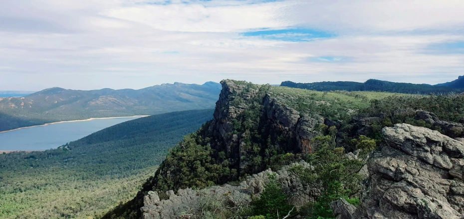 mountains and lake in the distance, with a lone bench on top of one of them