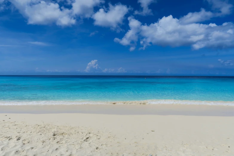 a sandy beach with ocean water and clouds