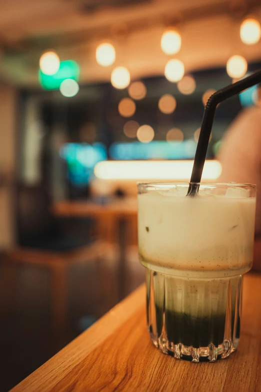 a drink sitting on top of a wooden table next to a person