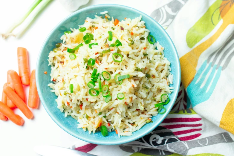 rice in a blue bowl with green onions and carrots